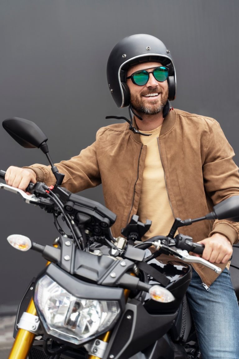 Bearded brutal biker wearing helmet and stylish sunglasses preparing riding motorbike